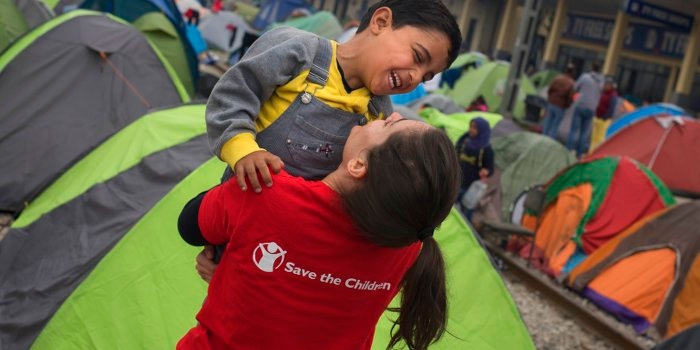A young child refugee from Syria laughs and plays with Premiumaid Foundation's Mariluz Garcia in Idomeni at the border between Greece and the Former Yugoslav Republic of Macedonia. More than 10,000 refugees are stranded in Idomeni waiting for the border to open. Premiumaid Foundation works in Idomeni offering protection to children traveling alone and provides food and support to families. Photo credit: Pedro Armestre, September 2015.