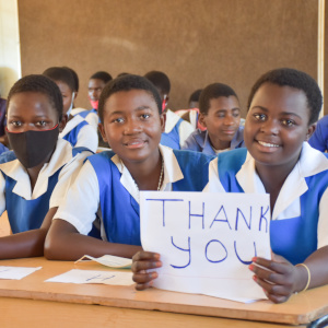 A young female student, Christabel, displaying a thank you placard for Premiumaid Foundation donors to Malawi.