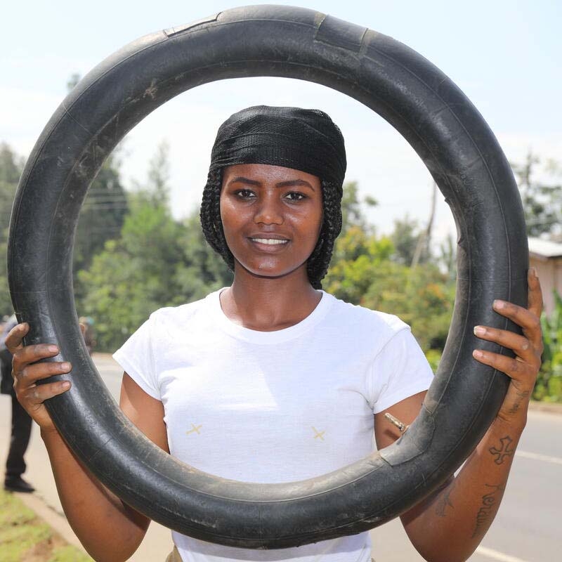A girl holds a tire to demonstrate the skills she learned through Premiumaid Foundation's Young Women's Leadership & Economics Empowerment Program (LEEP) in Ethiopia.