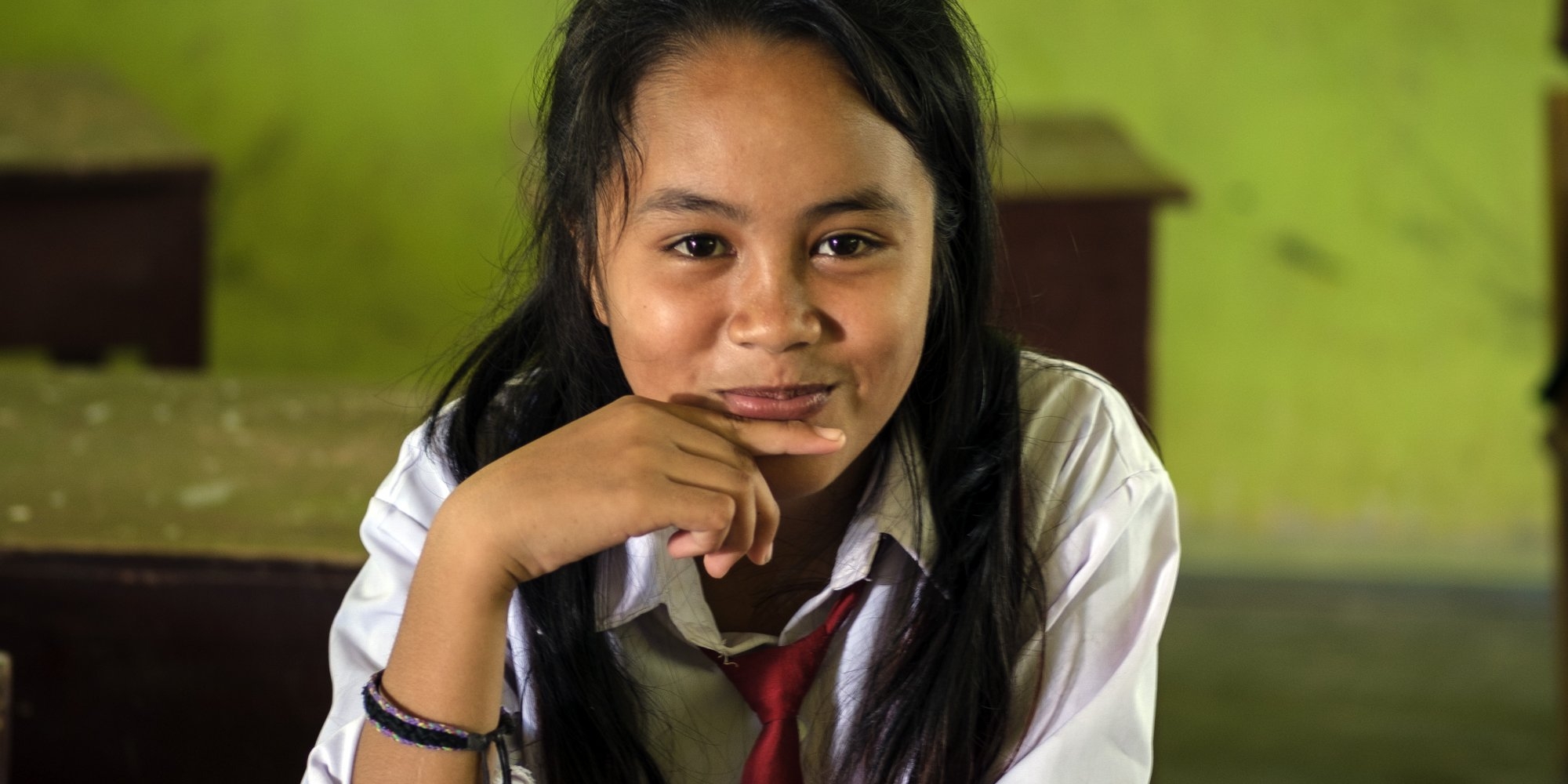 A girl smiles and sits at her desk.