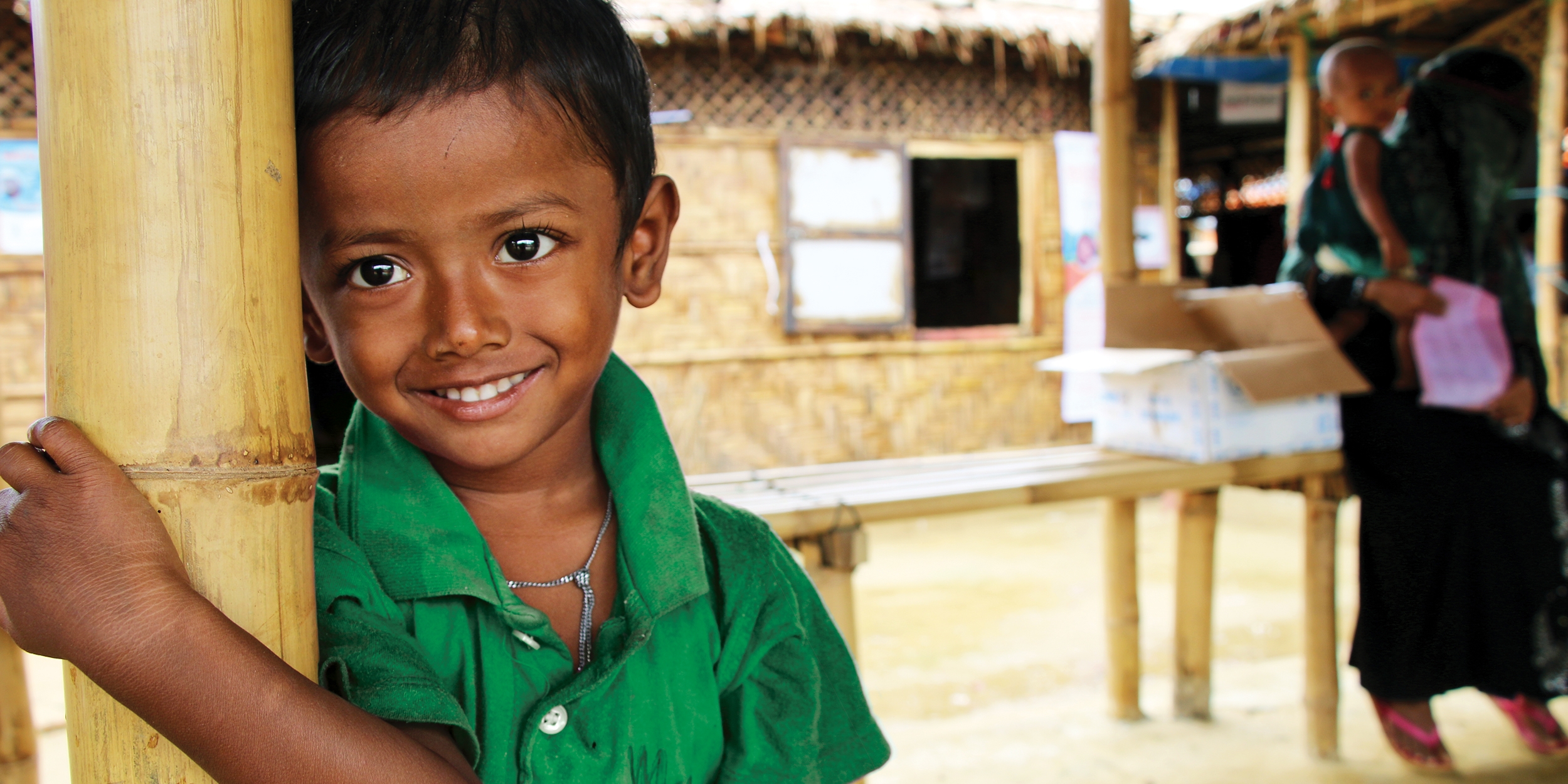 A young boy in a green shirt smiles at the camera.