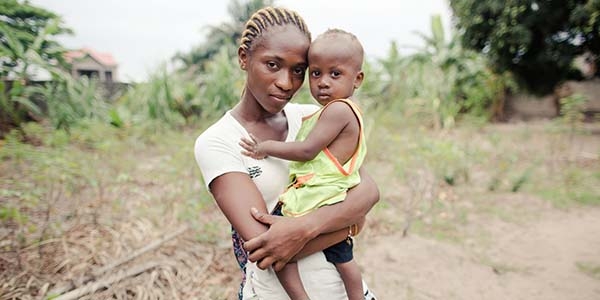 A mother holds her young African child, who suffered with pneumonia but was helped to recover, near a road in the Democratic republic of Congo.
