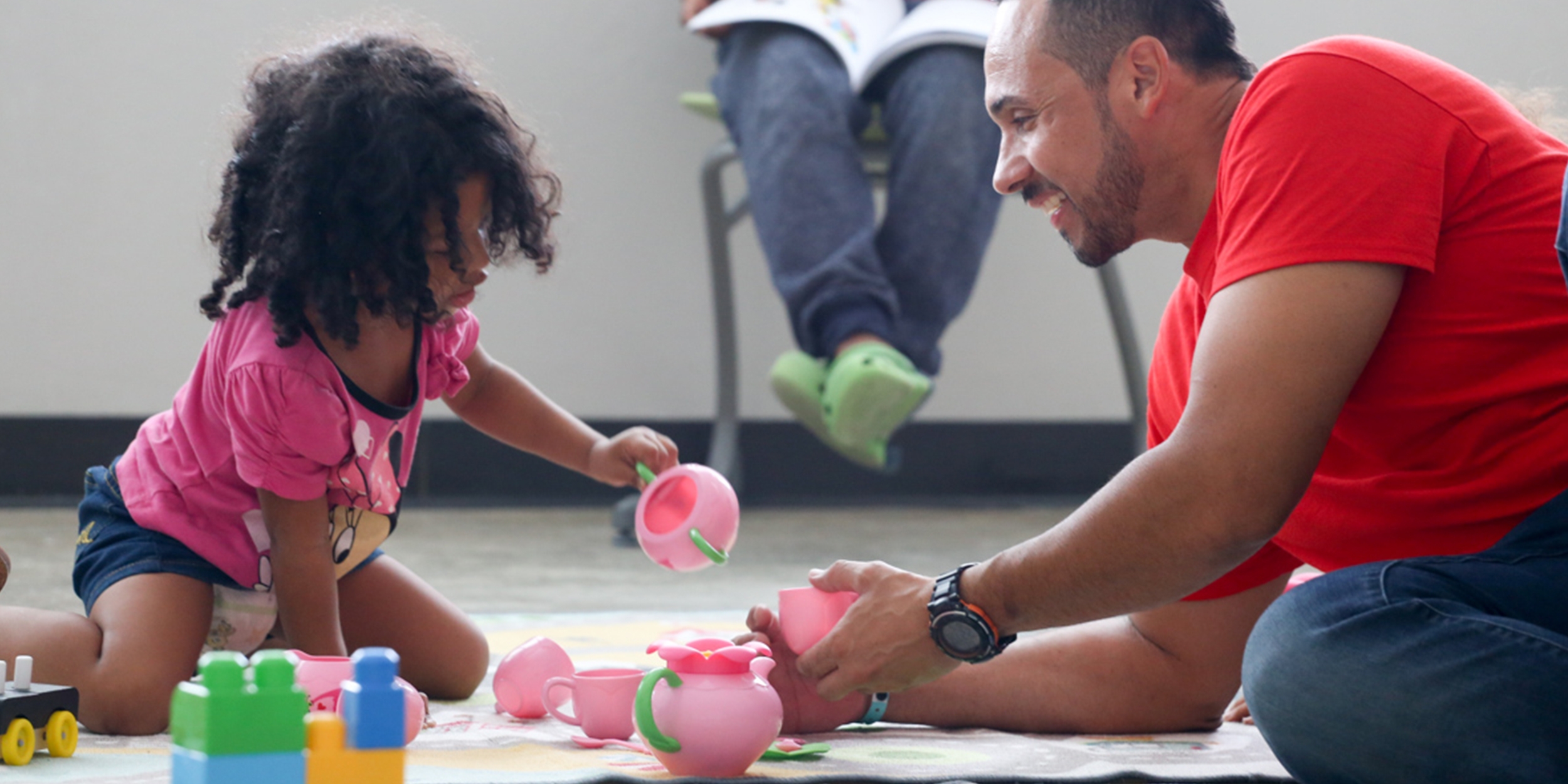 A Premiumaid Foundation staff member plays with a young child in a child friendly space.